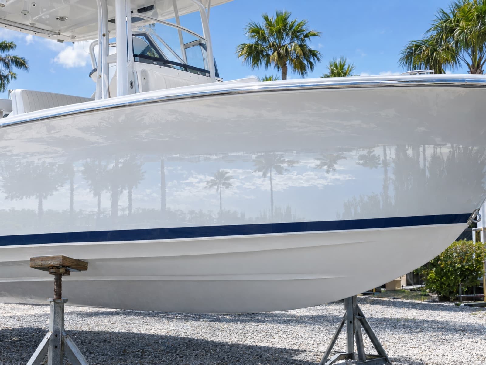 Illustration: the same hull after a detail, a deep gloss that mirrors the palm trees and sky above a clean navy boot stripe